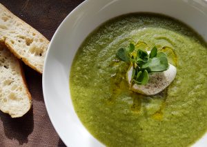 a green soup with bread on the side